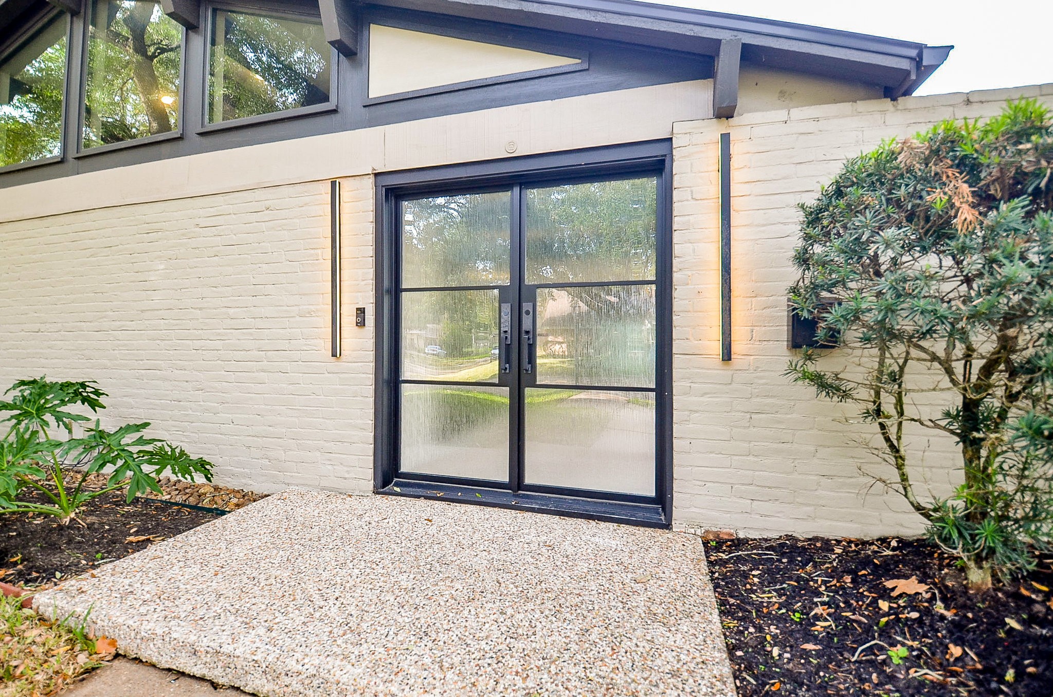 10003 Burgoyne Road Houston, TX 77042 - Photo 7 of 48 Welcome to 10003 Burgoyne! Custom modern metal-framed exterior double doors with frosted privacy glass panels, set a sophisticated first impression without compromising privacy, hinting at the home's refined mid-century influence