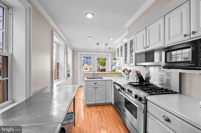 a kitchen with stainless steel appliances granite countertop a stove top oven a sink dishwasher and a refrigerator with wooden floor