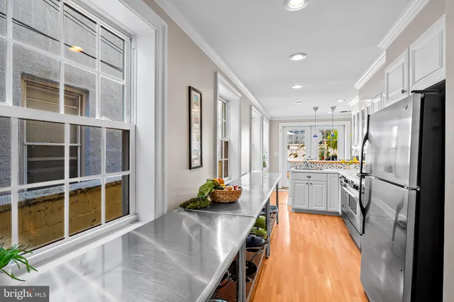 a kitchen with stainless steel appliances wooden floor and a refrigerator