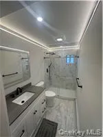 a bathroom with a granite countertop sink a toilet a mirror and shower