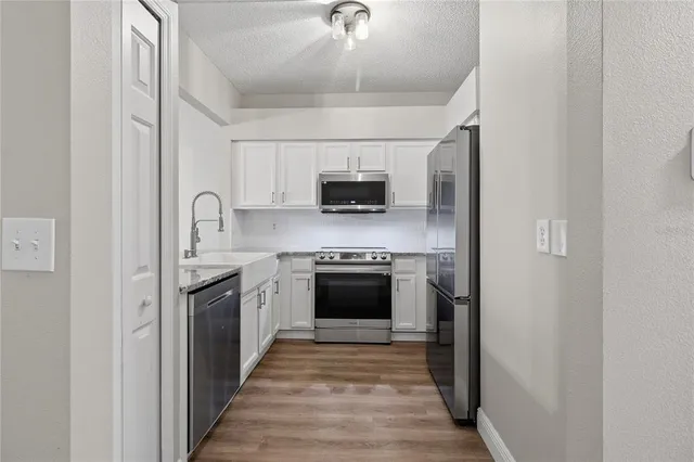 a kitchen with stainless steel appliances granite countertop a stove top oven a sink and a refrigerator