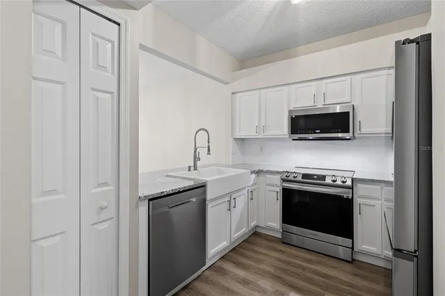 a kitchen with stainless steel appliances granite countertop white cabinets a sink and a stove