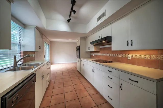 a large kitchen with granite countertop a sink stainless steel appliances and cabinets