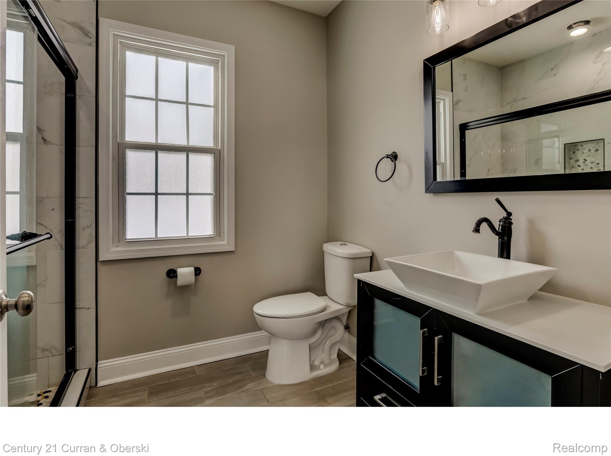 641 Josephine Street Detroit, MI 48202 - Photo 10 of 11 Bathroom featuring a modern vanity with a vessel sink, a dark-framed mirror, and a window with privacy glass