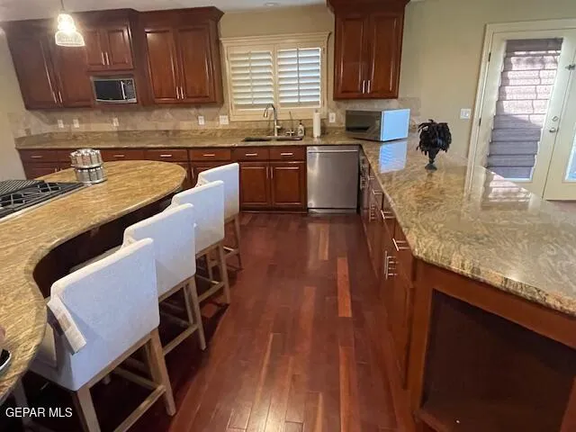 a kitchen with stainless steel appliances granite countertop a stove top oven a sink dishwasher and cabinets with wooden floor