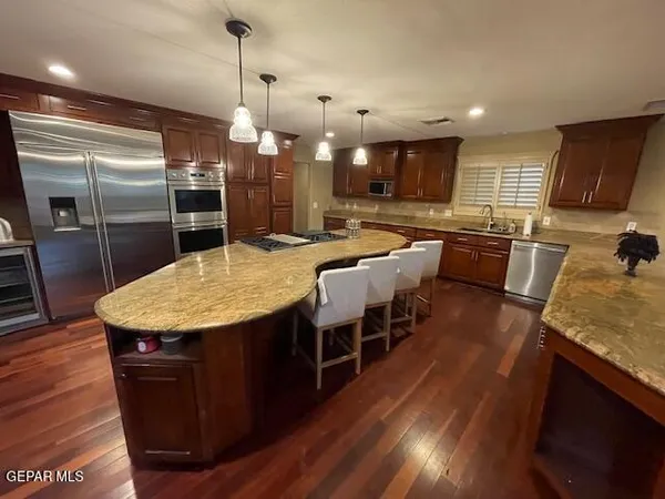a kitchen with stainless steel appliances kitchen island granite countertop a table chairs and a refrigerator