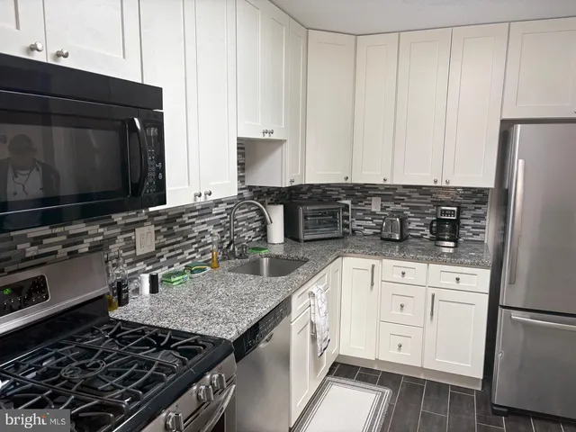 a kitchen with granite countertop a sink stove and refrigerator