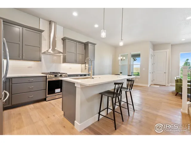 a kitchen with stainless steel appliances kitchen island granite countertop a table chairs sink and cabinets