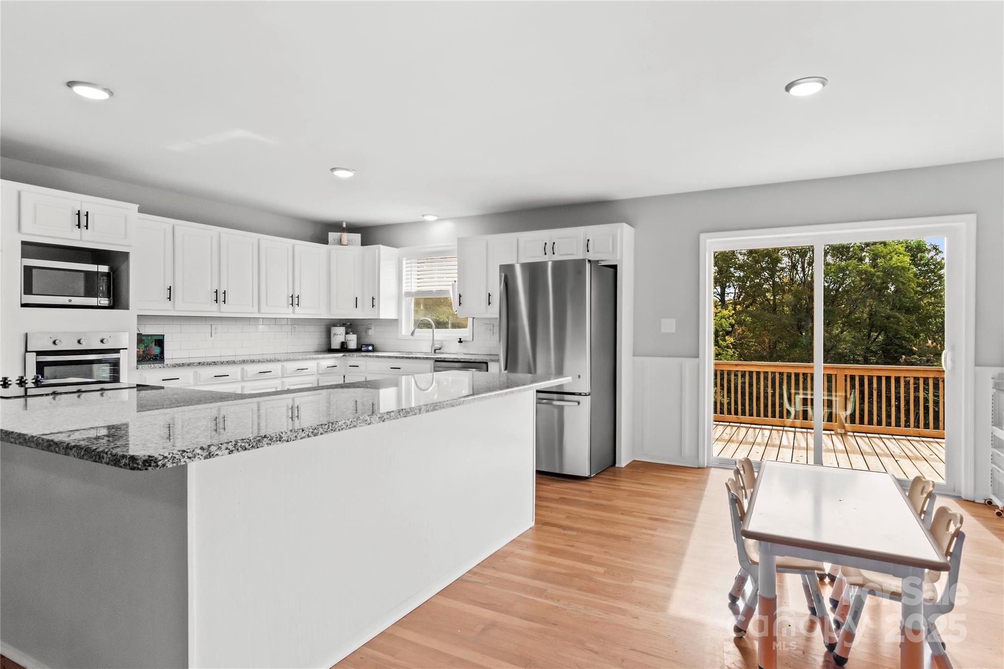 1627 Stony Knoll Road Dobson, NC 27017 - Photo 12 of 43 a kitchen with stainless steel appliances granite countertop a refrigerator a stove top oven a sink dishwasher and white cabinets with wooden floor
