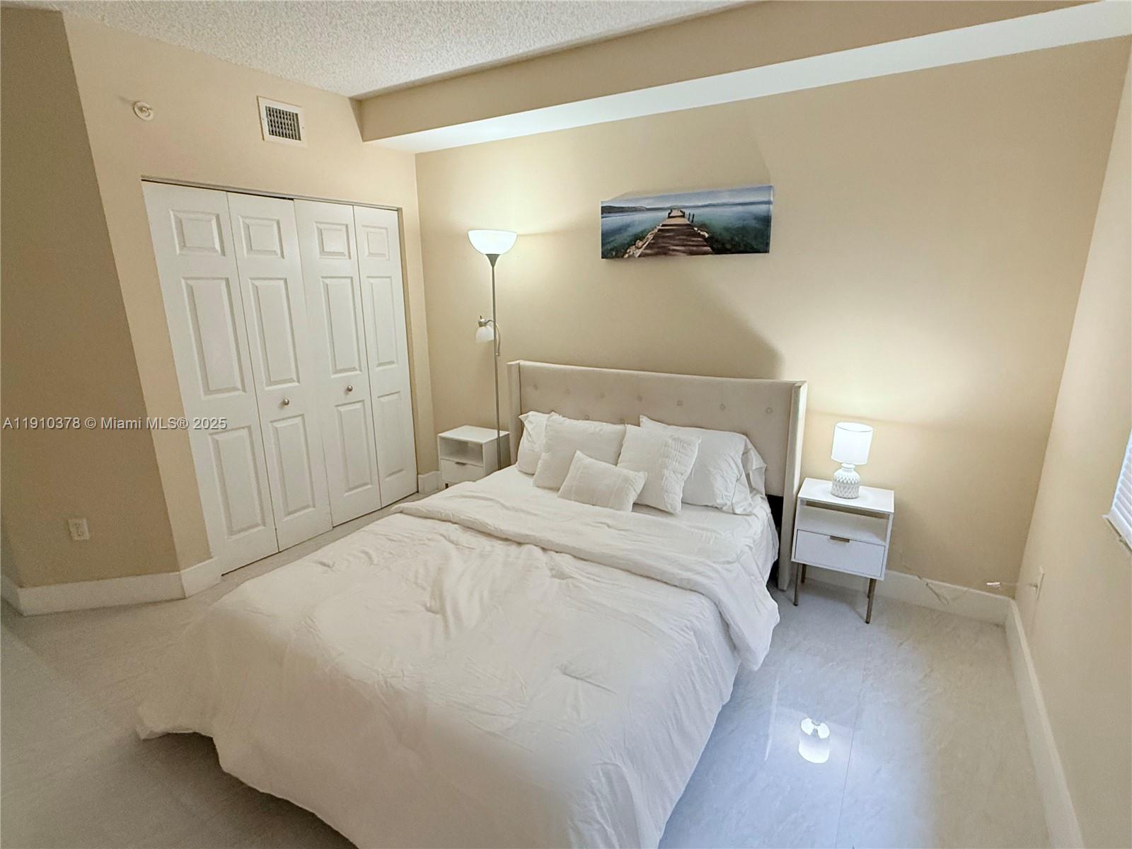 17150 North Bay Road, Unit 2102 Sunny Isles Beach, FL 33160 - Photo 10 of 29 a bedroom with a bed and a lamp on the dresser