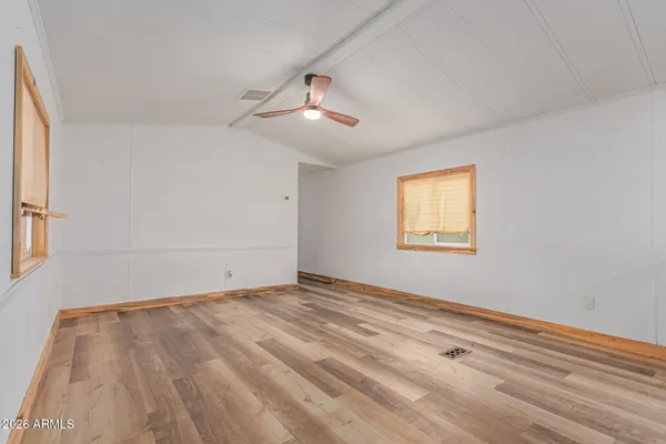 a view of empty room with wooden floor and fan