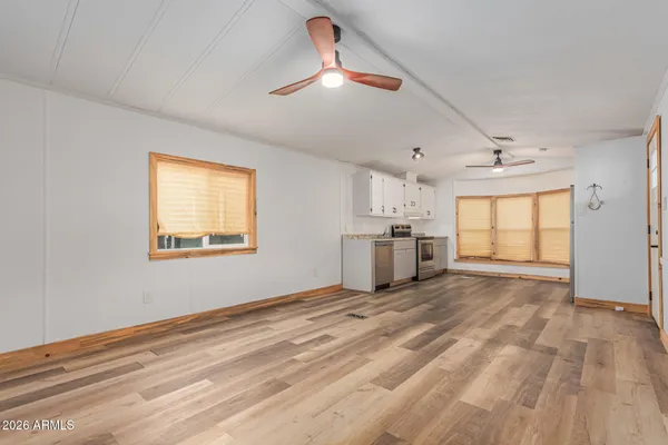 a view of an empty room with window and kitchen view