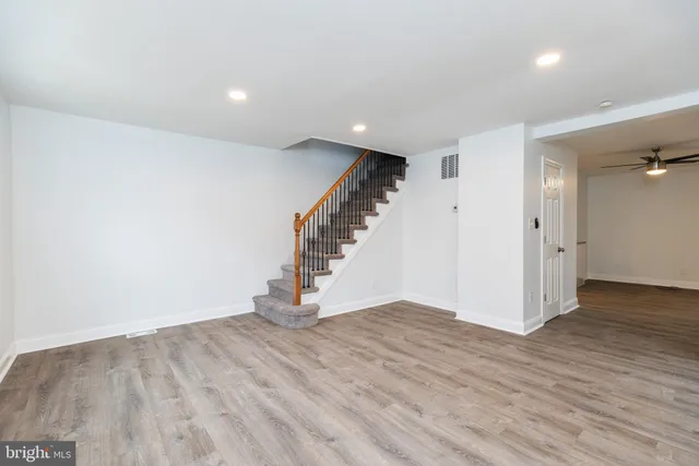 a view of an empty room with wooden floor and stairs