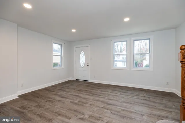 a view of an empty room with wooden floor and window