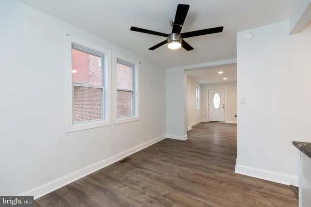 an empty room with wooden floor fan and windows