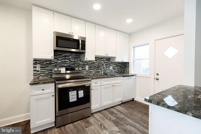 a kitchen with stainless steel appliances granite countertop a stove a sink and a microwave