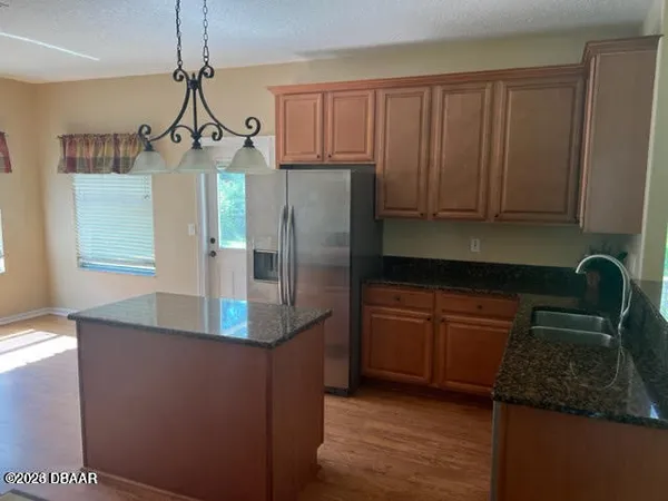 a kitchen with stainless steel appliances granite countertop a refrigerator a stove and a sink with wooden cabinets