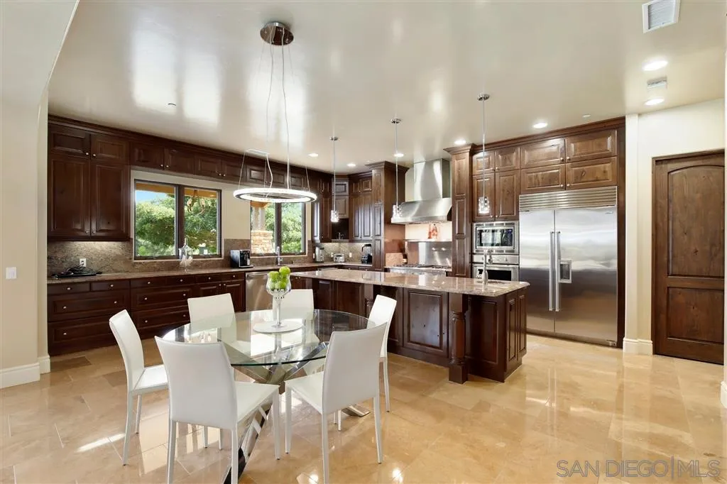 4142 Bridlewood Road Fallbrook, CA 92028 - Photo 9 of 25 a dining room with stainless steel appliances kitchen island granite countertop a dining table chairs and a refrigerator