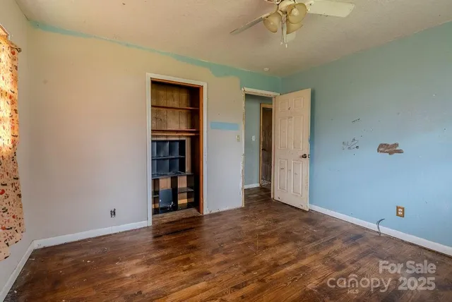 a view of an empty room with wooden floor and cabinet