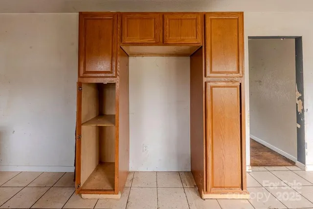 a view of an empty room with window and chandelier fan