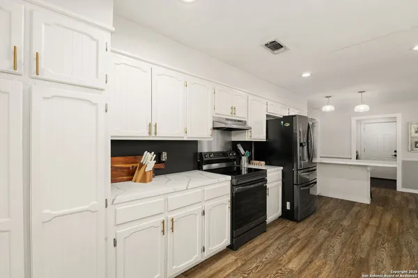 a large kitchen with sink cabinets and wooden floor