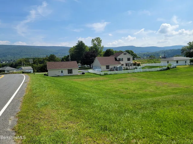 a view of a swimming pool with lawn chairs and large trees