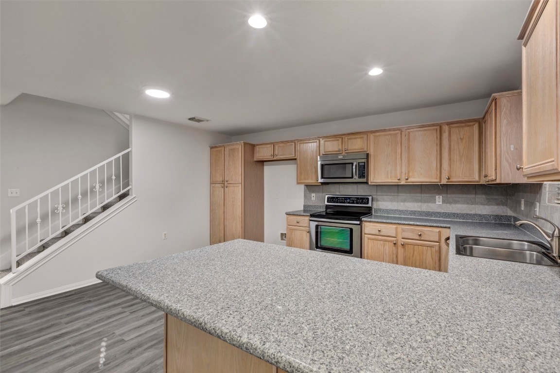 770 Hunt Road, Unit 212 Baytown, TX 77521 - Photo 17 of 40 a kitchen with granite countertop a stove top oven a sink dishwasher a refrigerator and cabinets with wooden floor