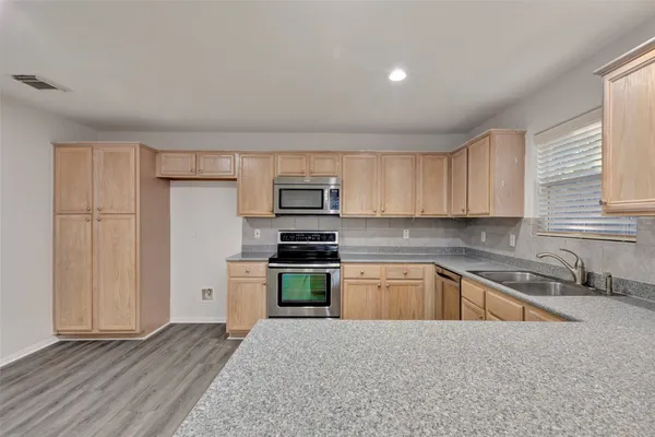 a kitchen with a sink a stove a refrigerator and white cabinets