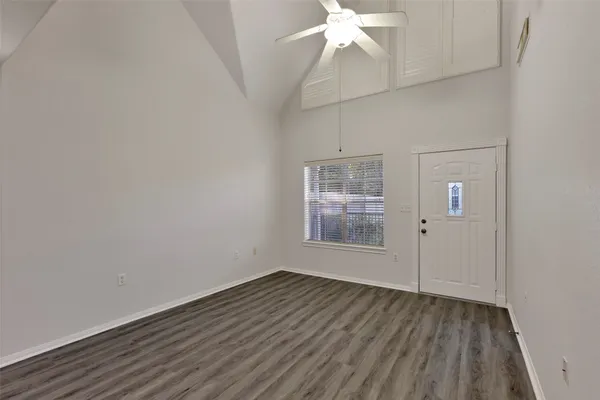 a view of a room with wooden floor a chandelier fan and windows