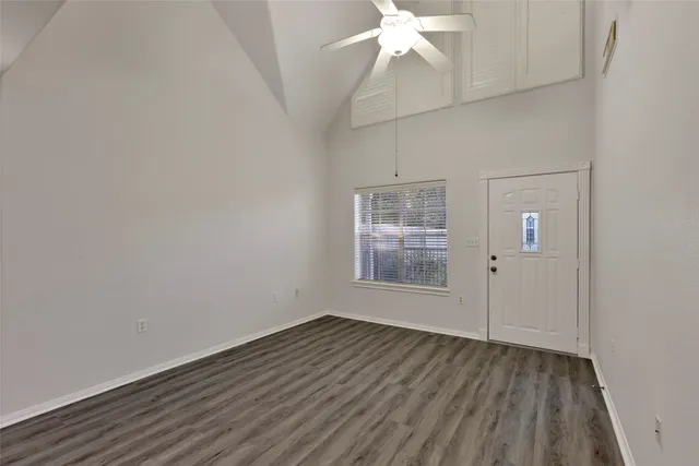 a view of a room with wooden floor a chandelier fan and windows