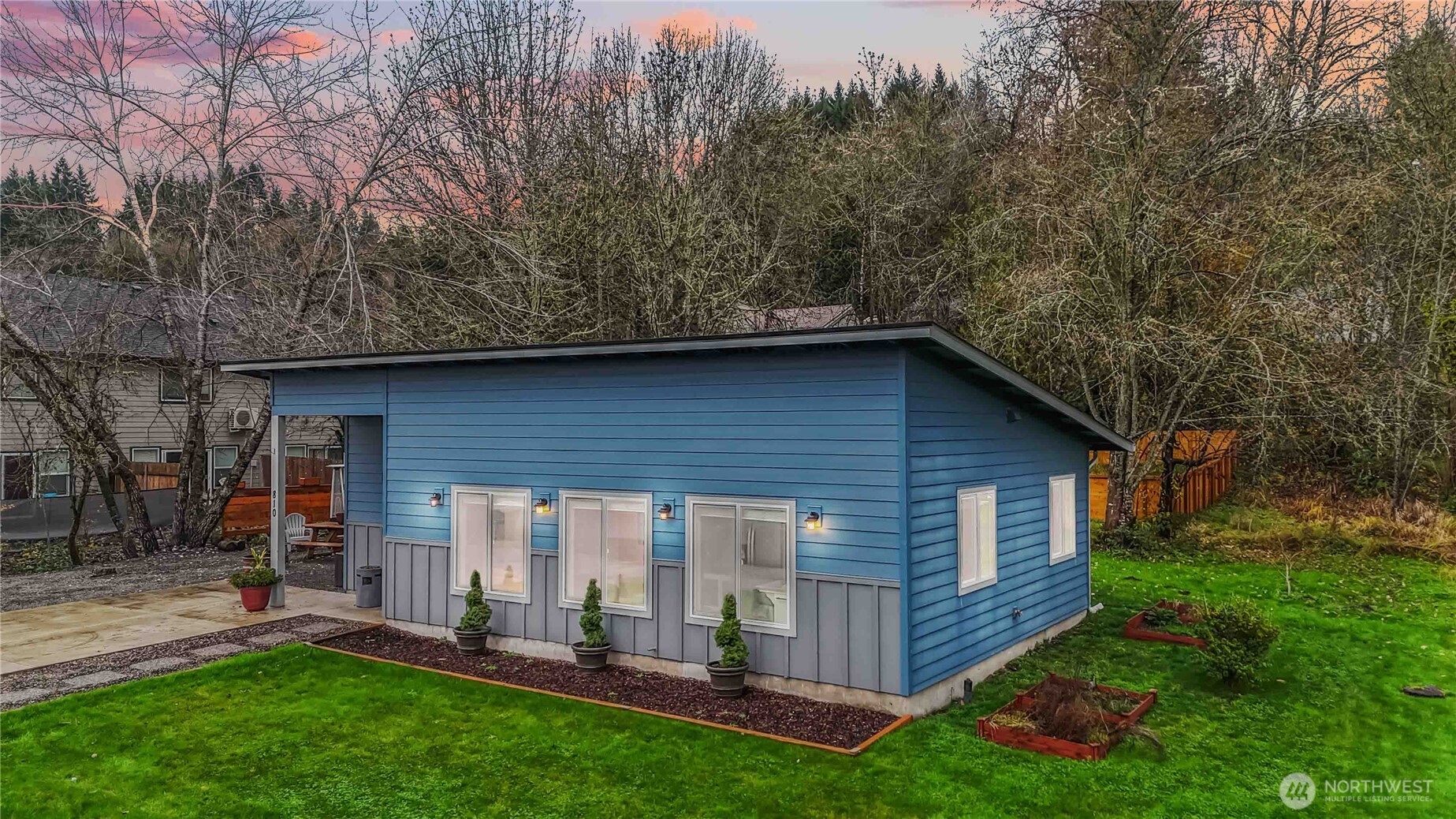 a view of a backyard with table and chairs and potted plants and large trees
