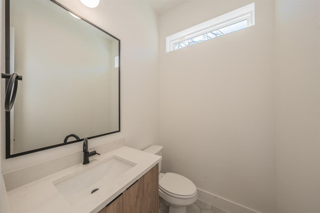 5320 Reiger Avenue, Unit 102 Dallas, TX 75214 - Photo 10 of 33 a bathroom with a toilet a sink and mirror