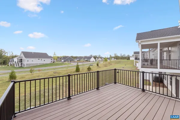 a view of an empty room with wooden floor stairs and a way to kitchen