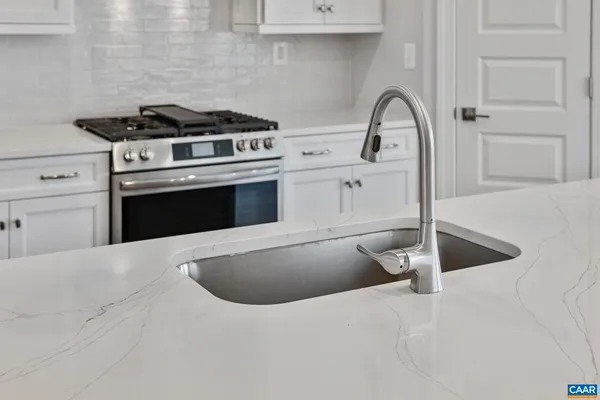 a kitchen with stainless steel appliances granite countertop a sink a stove and a wooden floors