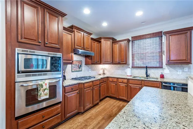 a kitchen with stainless steel appliances granite countertop a table chairs and a refrigerator