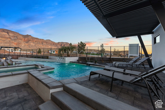 3558 South Cypress Road Hurricane, UT 84737 - Photo 39 of 57 Pool at dusk with a patio area, pool water feature, a mountain view, and an in ground hot tub