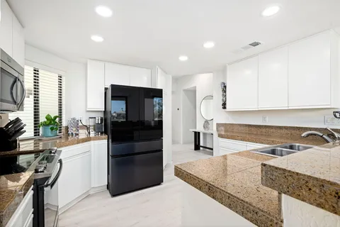 a kitchen with stainless steel appliances granite countertop a refrigerator a stove and a sink with wooden floor