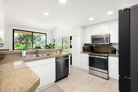 a kitchen with stainless steel appliances granite countertop a stove a sink and a refrigerator