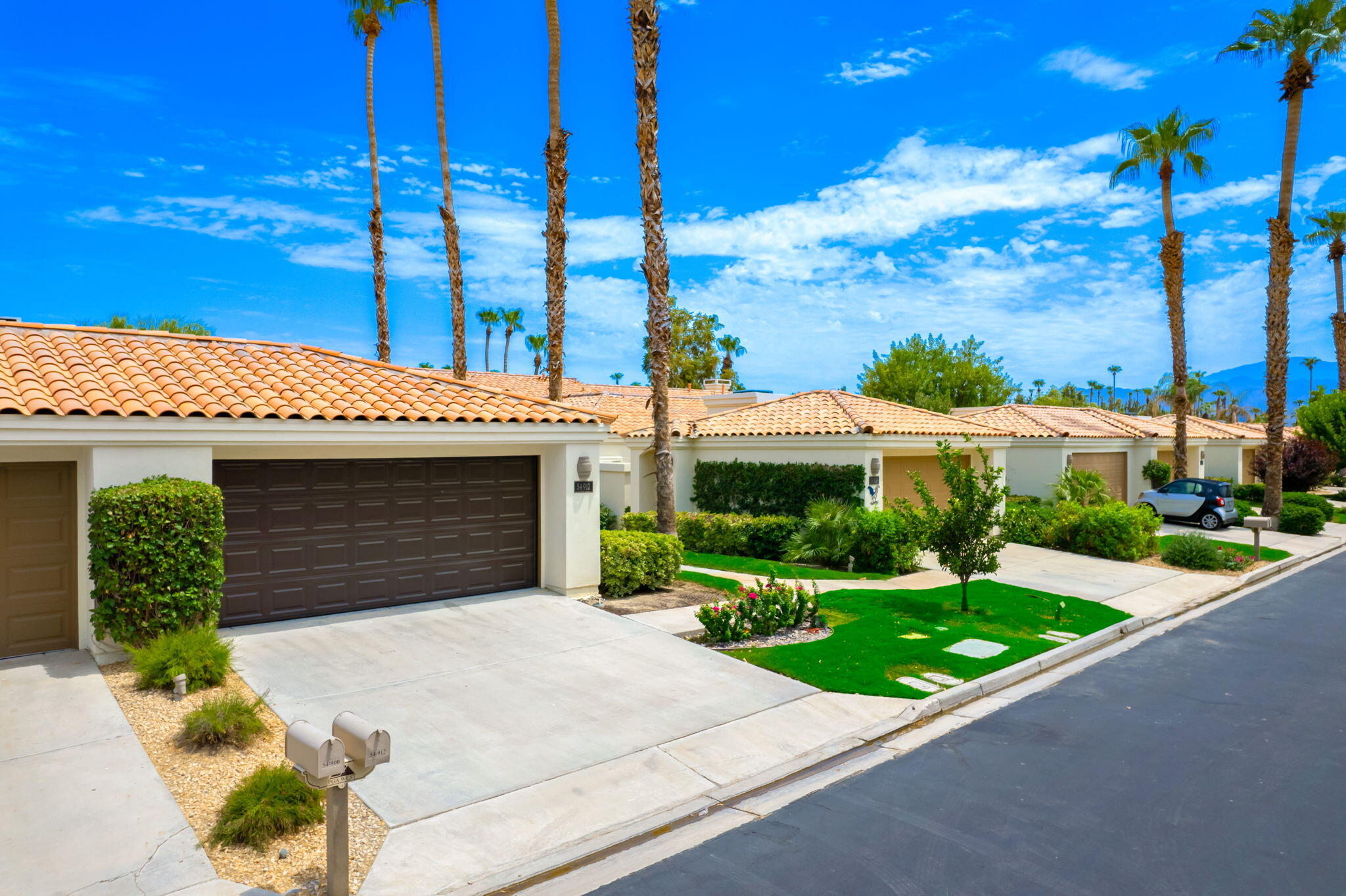 54912 Shoal Creek La Quinta, CA 92253 - Photo 23 of 36 a view of a white house with a yard and potted plants