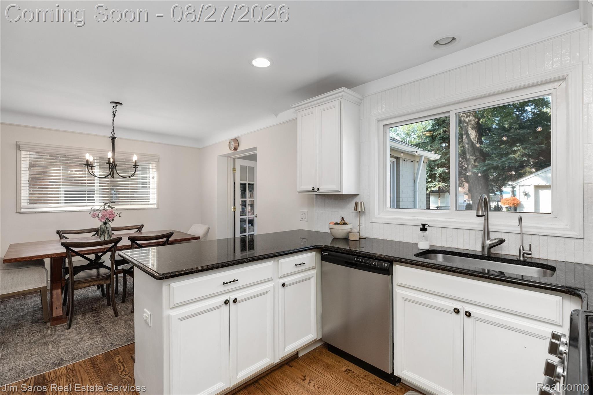 Kitchen featuring white cabinetry, dark countertops, a stainless steel dishwasher, and a stainless steel sink with a gooseneck faucet