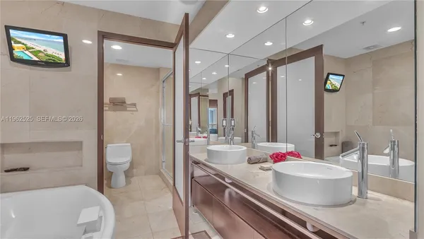 a bathroom with a tub sink mirror and toilet