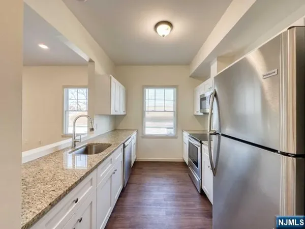 a kitchen with a refrigerator a sink and wooden floor