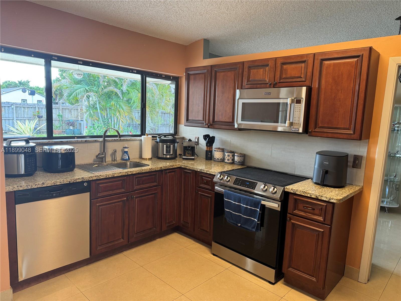 14700 Southwest 151st Terrace Miami, FL 33196 - Photo 2 of 19 a kitchen with stainless steel appliances granite countertop a stove sink microwave and window