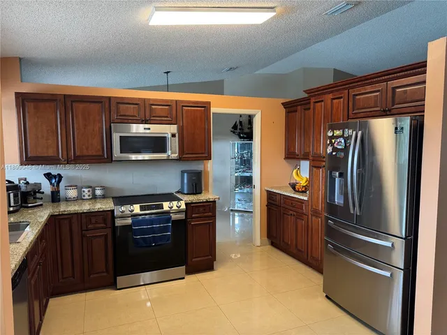 a kitchen with stainless steel appliances granite countertop a refrigerator stove and microwave