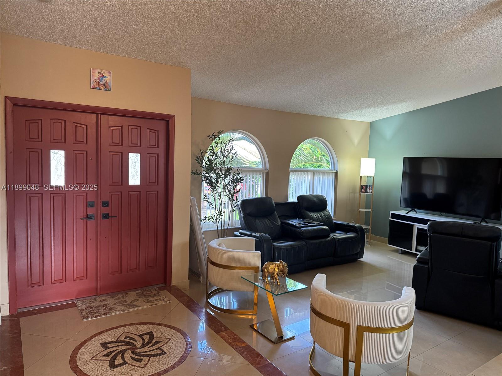 14700 Southwest 151st Terrace Miami, FL 33196 - Photo 6 of 19 a living room with furniture a flat screen tv and a floor to ceiling window