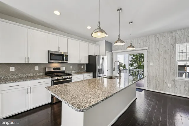 a large kitchen with stainless steel appliances granite countertop a sink a stove and a wooden floors
