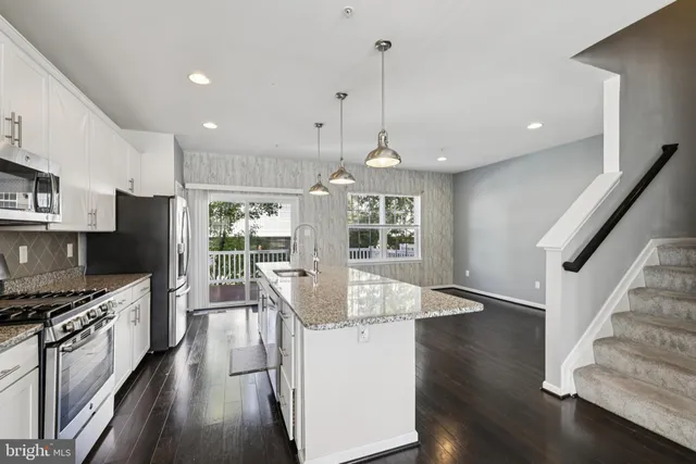 a kitchen with stainless steel appliances granite countertop a stove refrigerator and a wooden floor