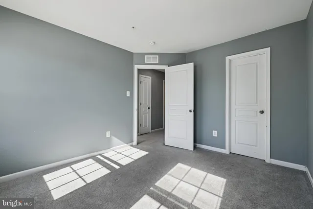 a view of an empty room with wooden floor and windows