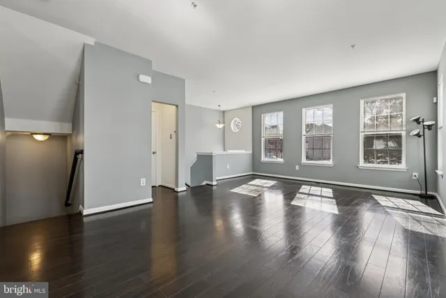 a view of an empty room with window and wooden floor