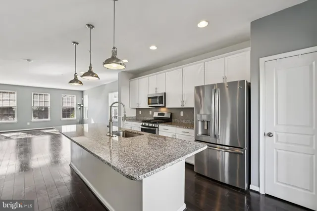 a kitchen with stainless steel appliances granite countertop a refrigerator a stove a sink and a center island